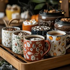 four coffee mugs filled with different types of food on a wooden tray next to other desserts