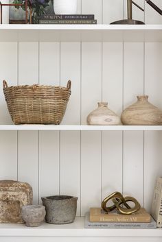 three shelves with vases, baskets and books on them