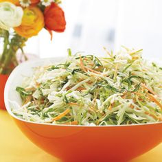 a bowl filled with coleslaw and carrots on top of a yellow table