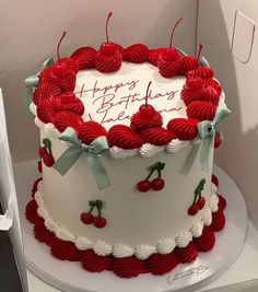 a white and red birthday cake with cherries on it