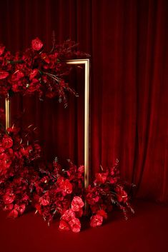 red flowers are placed in front of a gold frame on a red background with curtains