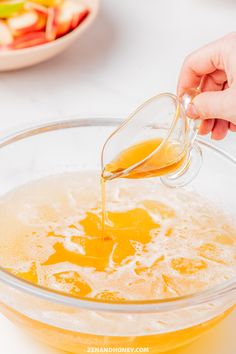 someone is pouring orange juice into a bowl