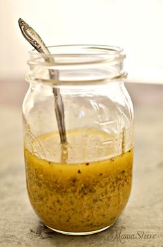 a glass jar filled with yellow liquid and a spoon