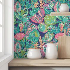 two white vases sitting on top of a wooden shelf next to a wallpaper