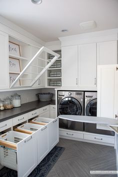 a washer and dryer in a room with white cupboards on the wall