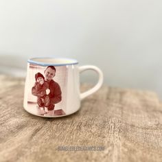 a coffee mug with an image of a man and child on it sitting on a wooden table