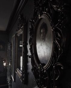 an old fashioned mirror hanging on the wall in a dark room with two framed pictures