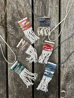 four pieces of weaving hanging from strings on wooden planks with string attached to them