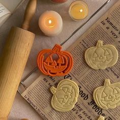 cookie cutters are sitting on top of a newspaper next to candles and pumpkins