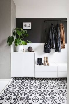 a black and white tiled floor in a room with coat racks, shoes and plants