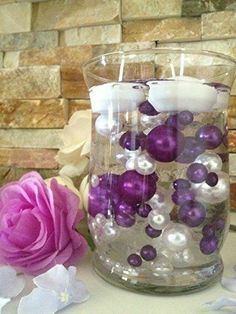 two vases filled with purple and white pearls next to a pink rose on a table