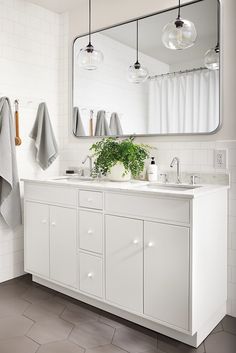 a white bathroom with two sinks, mirrors and towels hanging on the wall above them