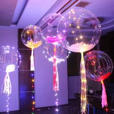 three large balloons with tassels and lights hanging from them in the middle of a room