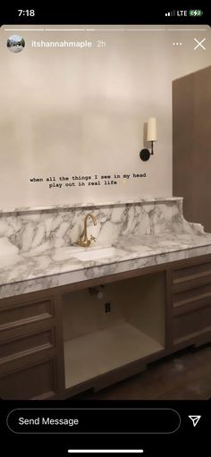 a bathroom vanity with marble counter top and gold faucet in front of it