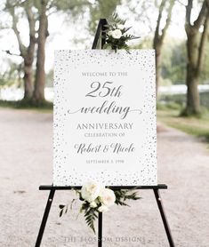 a sign with flowers and greenery on it for an anniversary party or wedding reception