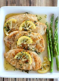 chicken with lemon and asparagus on a white plate