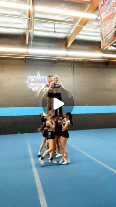 a group of young women standing on top of each other in a blue gym floor