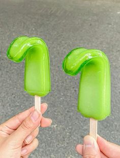 two hands holding green pops with the top one shaped like a number and the other half turned upside down