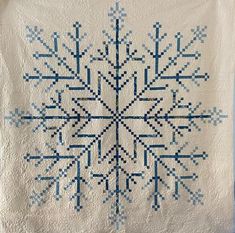 a blue and white snowflake quilt hanging on a wall