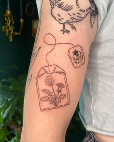 a person with a tattoo on their arm has a bird and flowers in the vase