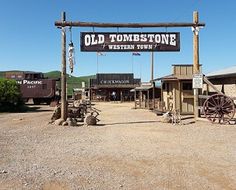 an old tombstonetone western town sign in front of a building with wagons and wagon wheels