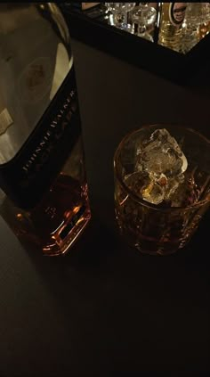 a bottle of whiskey sitting on top of a table next to a glass filled with ice