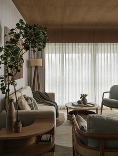 a living room filled with furniture next to a tall window covered in white drapes