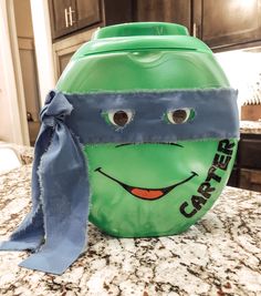 a green trash can with a blue ribbon around it's neck and the face of a teenage mutant