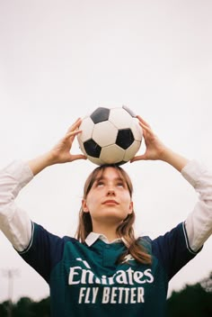 a woman holding a soccer ball on her head