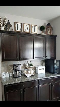 a kitchen with dark wood cabinets and white counter tops is pictured in this image, there are signs on the wall above the cupboards