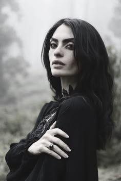 a black and white photo of a woman with her hands on her chest, looking at the camera