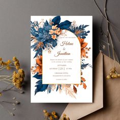 a wedding card with flowers on it next to an envelope and some dried yellow flowers