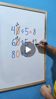 a man is writing numbers on a white board