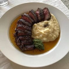 a white plate topped with meat and mashed potatoes