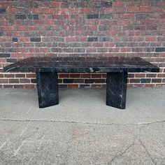 a black marble table sitting in front of a brick wall with no one around it