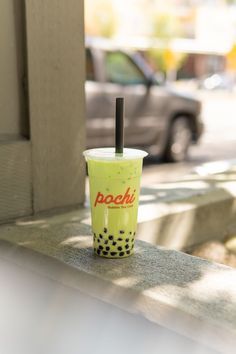 a yellow cup with a black straw in it sitting on the side of a building