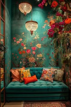 a blue couch sitting under a chandelier next to a wall covered in flowers