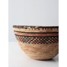 a woven bowl is shown on a white surface with an orange and black stripe in the center