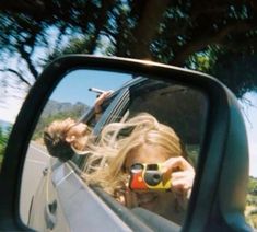 a woman taking a selfie in the side mirror of a car