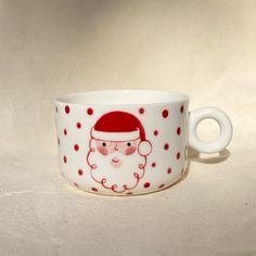 a white cup with a red santa claus face on it and polka dots around the rim