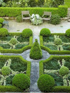 a formal garden with trimmed hedges and chairs