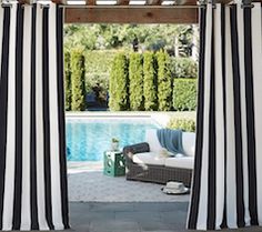 red and white striped curtains open in front of a swimming pool with an outdoor lounge area