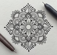 a pen and some ink sitting on top of a piece of paper with an intricate design