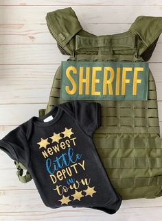 two baby onesuits, one with the name sheriff next to it and another with an infant's bodysuit