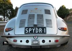 an old silver sports car parked on the side of the road with its license plate