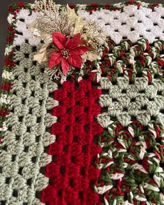 a crocheted blanket with poinsettia and holly on top is shown