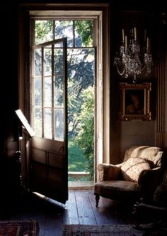 an open door leading to a living room with a chandelier hanging from the ceiling