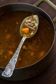 a ladle filled with soup on top of a wooden table