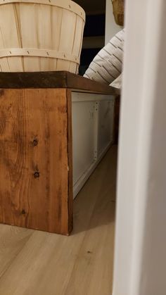 a basket sitting on top of a wooden table next to a white chair and pillows