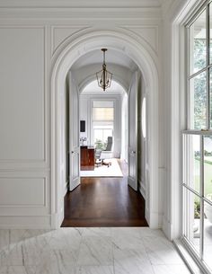 an archway leading to a living room with marble floors and white walls, along with two windows